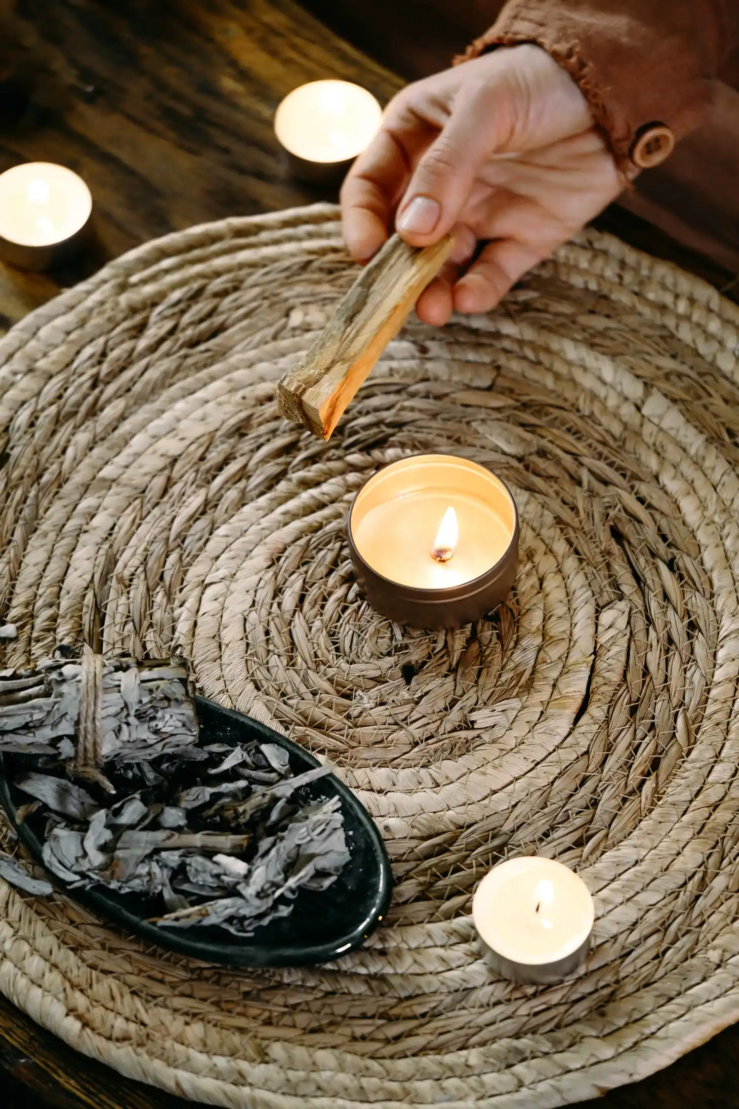woman-hands-burning-palo-santo-before-ritual-table-with-candles-green-plants-smoke